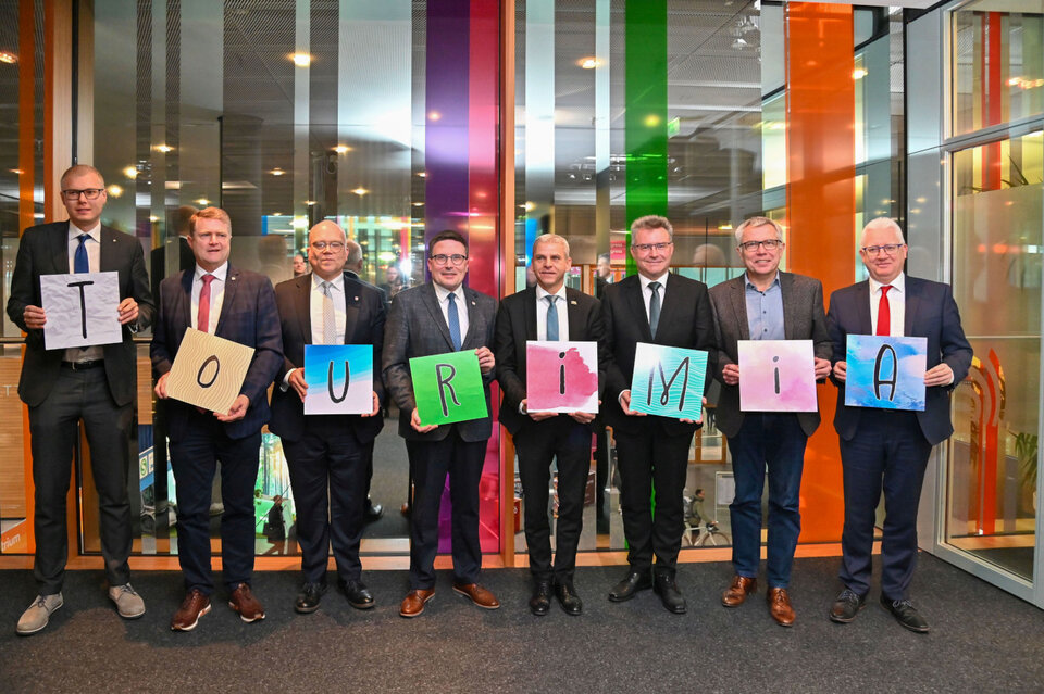 Oberbürgermeister Daniel Bullinger (Stellvertretender Vorsitzender Hohenlohe + Schwäbisch Hall Tourismus e.V.), Oberbürgermeister Martin Wolff (Vorsitzender Kraichgau-Stromberg Tourismus e.V.), Landrat Norbert Heuser (Vorsitzender Touristikgemeinschaft HeilbronnerLand e.V.), Landrat Christoph Schauder (Vorsitzender Tourismusverband „Liebliches Taubertal“ e.V.), Staatssekretär Dr. Patrick Rapp MdL (Ministerium für Wirtschaft, Arbeit und Tourismus Baden-Württemberg), Landrat Dr. Achim Brötel (Vorsitzender Touristikgemeinschaft Odenwald e.V.), Landrat Stefan Dallinger (Rhein-Neckar-Kreis) und Erster Landesbeamter Gotthard Wirth (Stellvertretender Vorsitzender Touristikgemeinschaft Hohenlohe e.V.) präsentieren den Namen der neuen touristischen Dach-DMO: Tourimia.