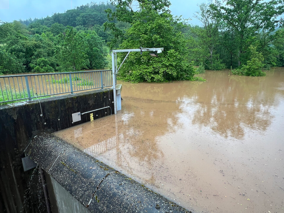 Das Hochwasserrückhaltebecken Glasofenbach in Rudersberg am 1. Juni 2024. Links ist ein gelb-schwarzer Lattenpegel zu sehen, rechts ein moderner Pegel. 