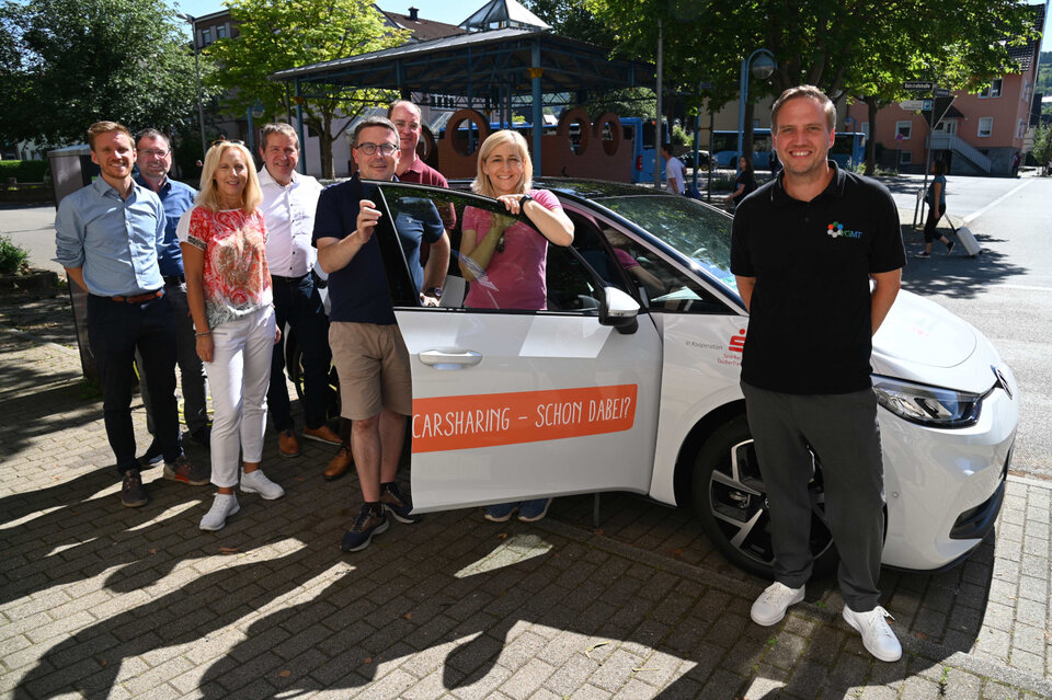 Das E-Auto an der Mobilitätszentrale in Lauda: Fabian Fluhrer (von links), Projektleiter für nachhaltige Mobilität beim Stadtwerk Tauberfranken, Siegfried Scheidel, Gruppenleiter Sparkasse Tauberfranken, Dezernentin Ursula Mühleck, Geschäftsführer Paul Gehrig, Stadtwerk Tauberfranken, Landrat Christoph Schauder, Bürgermeister Dr. Lukas Braun, Bundestagsabgeordnete Nina Warken und VGMT-Geschäftsführer Thorsten Haas freuen sich darüber, dass das Sharing-Angebot der Mobilitätszentrale Lauda jetzt vollständig ist. 